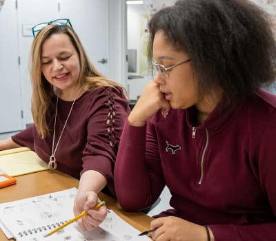 A student and mentor looking at a sketchbook